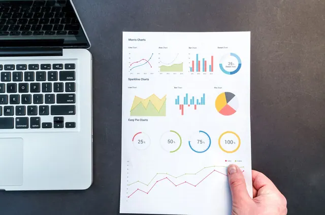 Detailed charts and graphs on a document next to a laptop, representing data analysis. Analytics foundations metrics: facts, examples and context